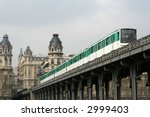 paris metro train on a bridge emerging from in-between two close buildings