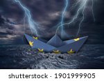 Small photo of EU paper boat made as the flag of the European Union almost capsizes in high waves and bolt of lightning over stormy dark sea during a thunder-storm with dramatic cloudscape. Europe problems concept.