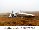 The upside down wreckage of a light aircraft on a high, fog covered mountain