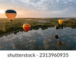 Colorful hot air balloons over lake at sunrise