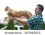 Small photo of Man holding his cherished purebred Maine Coon cat outright to show his size. Shallow depth of field.