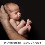 Small photo of Newborn Baby lying on Father Hand over Black Background. Child sleeping in Fetal Embryo position. Small Kid artistic Portrait. Baby Care and Parenting Concept