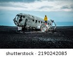 Woman in yellow jacket on Solheimasandur Plane Wreck in Iceland. Traveling in Iceland