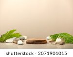 Small photo of Wood podium with green leaves and natural stones. Abstract podium for organic cosmetic products. Natural stand for presentation and exhibitions. Front view