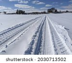 Tractor and wagon tire tracks across a winter swept corn field. Work on farm continues through the winter.
