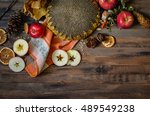 Small photo of Rural vintage autumn red apples, sunflower, pine cones, orange and apple slices on a rustic wooden background, natural fall style decorations. Natural plenteous border background vintage mock up.