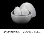 Small photo of Egg boiler contains four eggs on black background