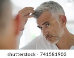 40-year-old man checking hair in front of mirror