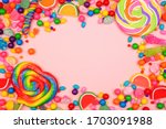 Colorful assortment of candies. Top view frame over a pink background.