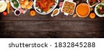 Small photo of Traditional Thanksgiving turkey dinner. Above view top border on a dark wood banner background with copy space. Turkey, mashed potatoes, dressing, pumpkin pie and sides.