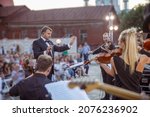 Small photo of Conductor directing orchestra performance on the street