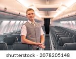 Male flight attendant standing in aircraft passenger salon