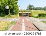 Deserted bicycle path passing under  a motorway on a sunny summer day