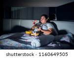 Unhealthy lifestyle concept: Overweight woman eating ice cream and junk food in bed before sleeping