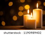 Close up of three burning candles on the wooden table with blurred Christmas light background