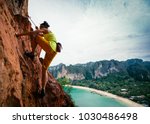 woman rock climber climbing on seaside cliff