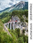 Small photo of Bernina express in Switzerland. Vertical view of Landwasser Viaduct, railroad bridge and red train in Swiss Alps. Alpine landscape with mountain Rhaetian railway. Travel and rail road in Switzerland.