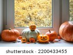 Small photo of Halloween pumpkins by window at home. Vegetables set, orange food, sweets and decorations on white windowsill on hallowen. Concept of October, fall, Halloween, still life, kitchen, season and holiday