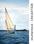 Small photo of Old expensive vintage two-masted sailboat (yawl) close-up, sailing in an open sea. Lighthouse in the background. Sport, cruise, tourism, recreation, leisure activity, transportation, nautical vessel