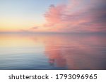 Baltic sea after the rain at sunset. Dramatic sky with glowing  pink clouds, symmetry reflections in the water. Abstract natural pattern, texture, background, concept art