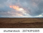 Small photo of Dramatic sky, dark clouds above the plowed agricultural field and forest. Rural scene. Atmospheric landscape. Early autumn. Nature, fickle weather, ecology, environment, farm industry, remote places