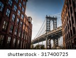 Manhattan bridge seen from a narrow alley enclosed by two brick buildings on a sunny day in summer