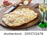 Small photo of Hearty tarte flambee from Alsace with onions, smoked bacon and munster cheese hot from the oven, served with Alsatian white wine