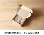 Opened cardboard box with wood excelsior shred filler on wooden background. View above