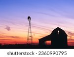 A beautiful sunset of a windmill and barn silhouetted against the evening sky in rural Indiana USA, North America