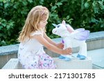 Small photo of Adorable little girl playing with unicorn. Preschool child having fun with soft stuffed toy