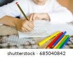 Child doing homework and writing story essay. Elementary or primary school class. Closeup of hands and colorful pencils.