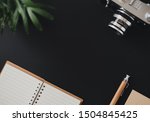 Small photo of Top view of a flat lay open notebook paper for notes pen and a film camera lie on a black countertop. Concept workplace of a journalist or writer. Advertising space