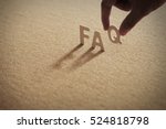FAQ word on compressed board with human's finger at Q letter