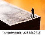 Miniature Businessman Standing on a Pile of Money Bills