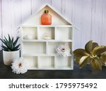 Small photo of A white house shadowbox with flowers, stones and essential oil