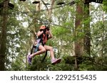 Young girl (female age 08) sliding on a flying fox zip line during a treetop adventure climbing. Girls power, risk and challenge concept. Real people. Copy space