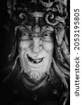 Small photo of Monster face of aGreek antique god daimon of eager rivalry, envy, jealousy, and zeal Zelus (Zelos). Fragment of an ancient stone statue. Vertical image.