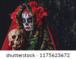 Calavera Catrina holding a skull over dark scary background. Sugar skull makeup. Dia de los muertos. Day of The Dead. Halloween. 