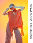 Small photo of Demi-season haute couture collection. Knitwear style. Stylish fashion model posing in wide leg trousers, knitted poncho and knitted cap in studio in mixed color light. Bright colors.