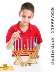 Small photo of Jewish boy using the shamash candle to light the menorah for Hanukkah.