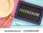 Food & Drink. Chalkboard with wooden spoon and plate on a red checkered tablecloth and text Food & Drink