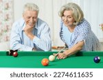 Happy senior couple playing billiards on vacation together in home