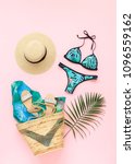 Small photo of Bikini swimsuit with tropical print, silver glitter flat sandans, straw hat, wicker beach bag, sarong, tropical palm leaves on pink background. Overhead view of woman's swimwear and beach accessories.