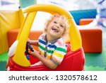 Child riding toy car. Little boy playing with big bus. Kid driving plastic truck in indoor playground or kindergarten. Toddler at day care play room. Toys for little boys. Daycare amusement center.