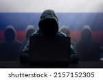 Small photo of Russian hacker at laptop. Malware and virus danger from Russia. Man in hoodie and dark mask hacking. Dark net and cyber crime. Identity theft. Criminal at work. Troll army.