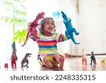 Small photo of Child playing with colorful toy dinosaurs. Educational toys for kids. Little boy learning fossils and reptiles. Children play with dinosaur toys. Evolution and paleontology game for young kid.