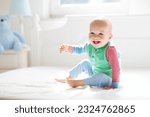 Small photo of Baby boy crawling on bed. Little child playing in white sunny bedroom. Infant kid learning to crawl. Nursery for children. Textile, clothing and bedding for kids. Family morning at home.