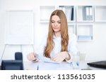 Portrait of a beautiful young smiling business woman doing some paperwork in bright office