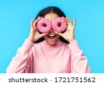 Portrait of beautiful  woman and donuts. Girl showing doughnuts in front of her eyes on blue background. Tasty food, diet concept                          