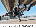 Small photo of Young man break dancer dancing on urban background performing acrobatic stunts. Street artist breakdancing outdoors